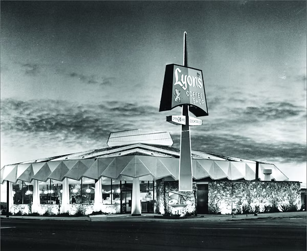 Black and white photograph of a retro-style restaurant building with a tall sign reading Lyon's Coffee Shop, set against a cloudy evening sky.