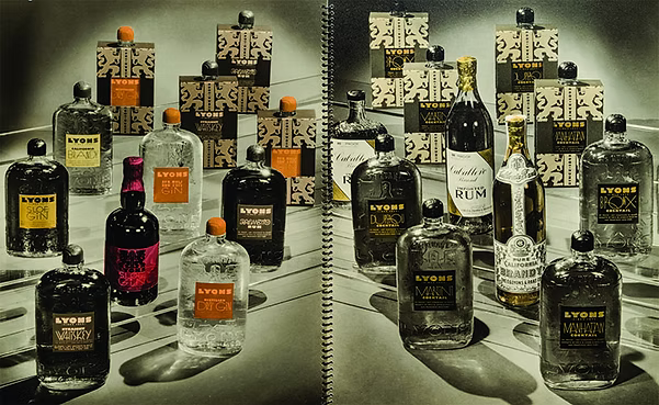 A vintage-style promotional display of multiple Lyons brand liquor bottles and boxes arranged on a reflective surface, with a spiral binding visible down the center. The bottles are mostly dark glass with some clear glass and a few featuring orange, pink, and gold accents on labels or caps.