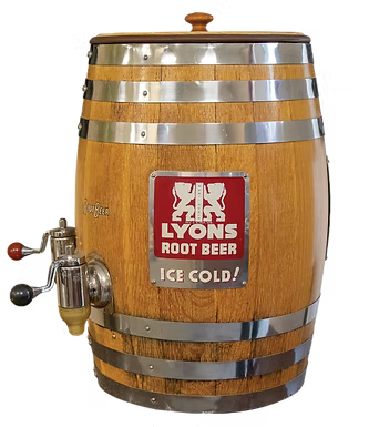 A wooden root beer barrel with stainless steel bands, a top lid, and a side metal tap. The front features a red and white 'Lyons Root Beer Ice Cold!' logo.