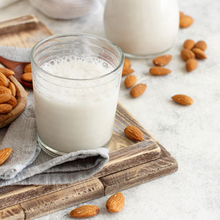 A glass of milk and almonds scattered on the table