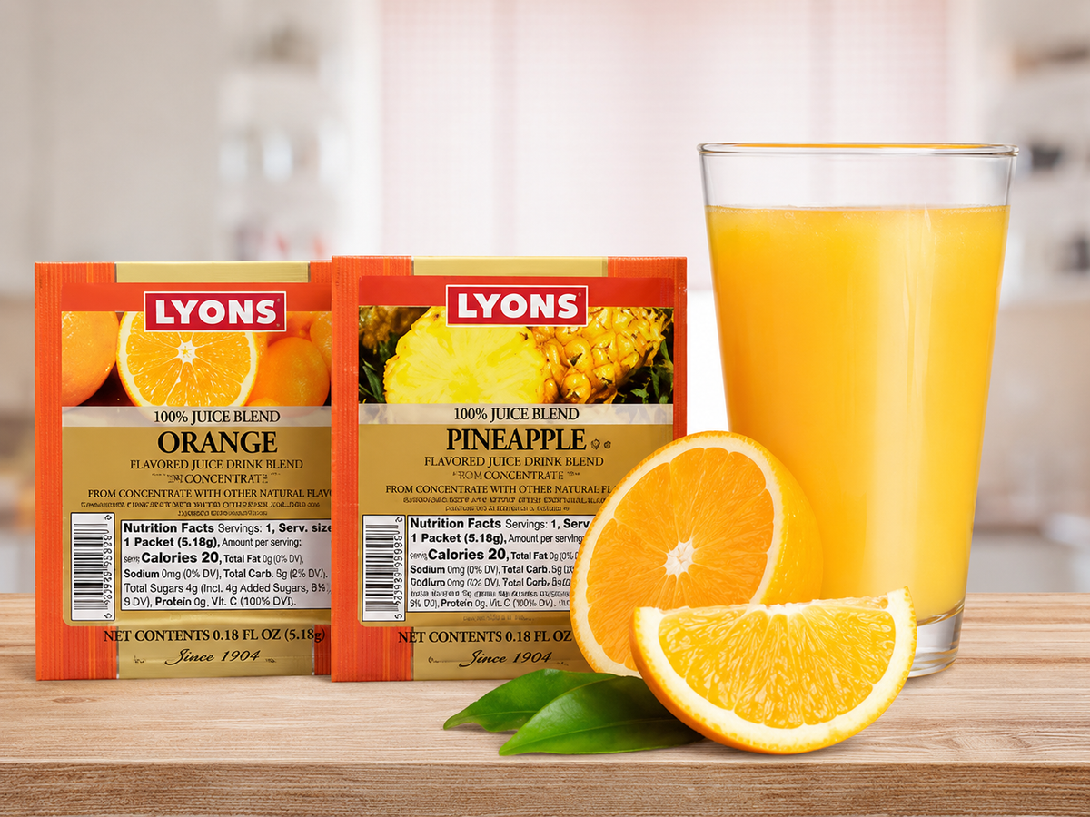 Two Lyons 100% juice blend tea packets, one orange-flavored and one pineapple-flavored, displayed on a wooden surface next to a glass of orange juice and sliced oranges.